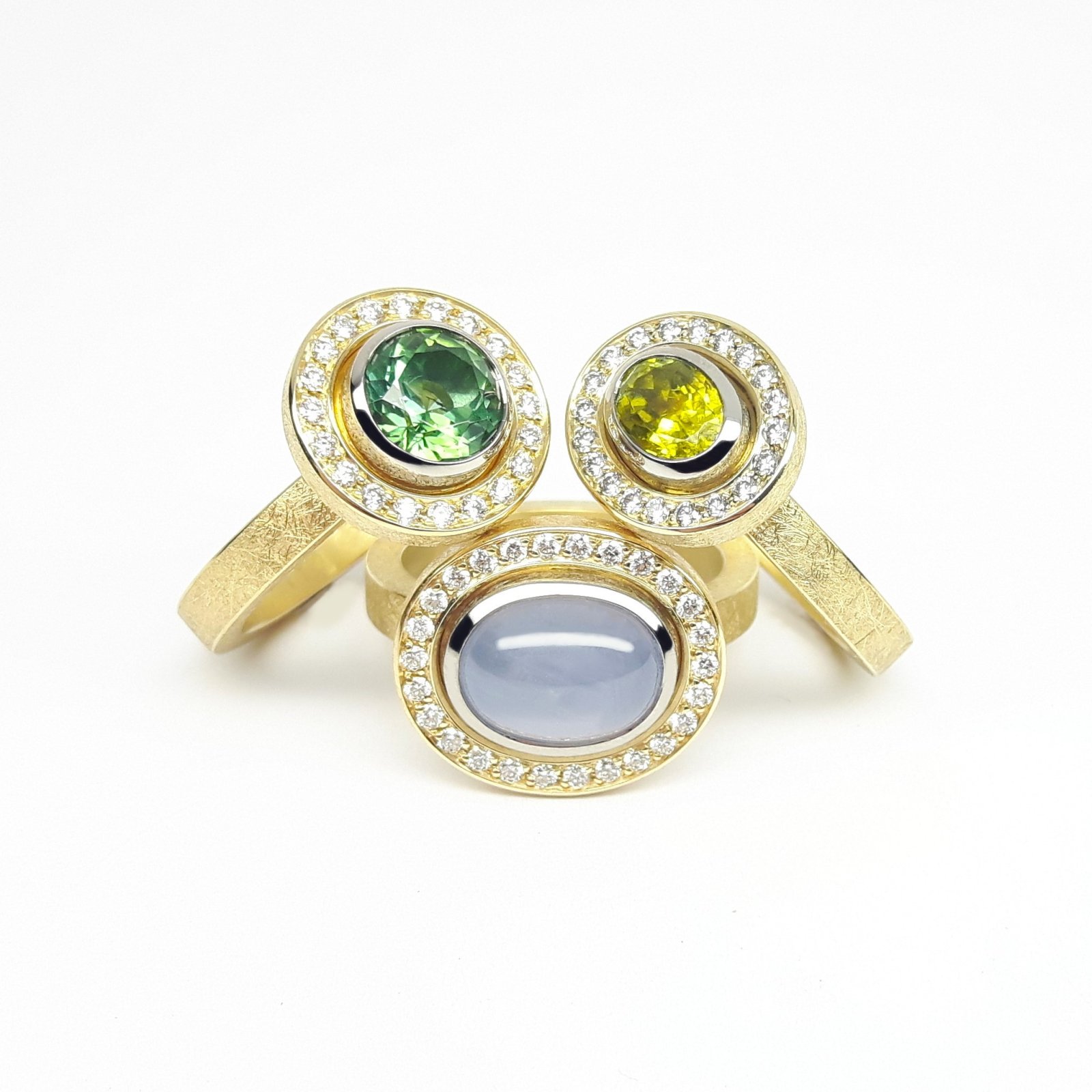trois bagues en or jaune avec des pierres précieuses de couleur vert et bleu , entouré des petites brillants.